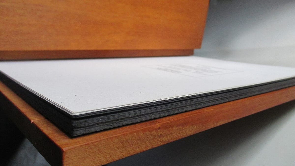 Ein aufgeschlagenes Buch mit dickem Papierblock, seitlich auf einer Holzfläche