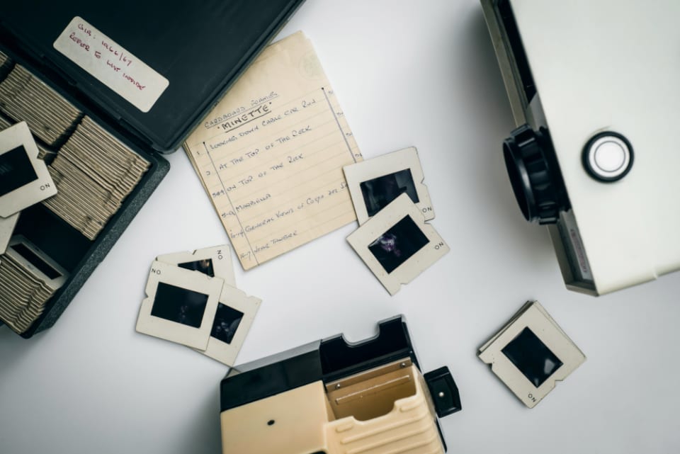 Gerahmte Kleinbild-Dias neben einem Betrachtungsgerät und handschriftlichen Notizen