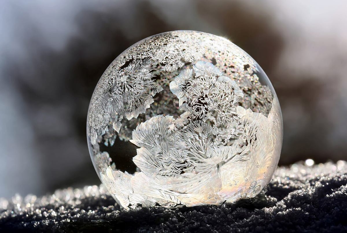 Eine gefrorene Seifenblase, auf der Oberfläche haben sich farnartige Eiskristalle gebildet