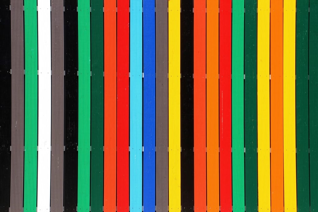 Senkrechte Holzlatten, jede in einer anderen kräftigen Farbe gestrichen