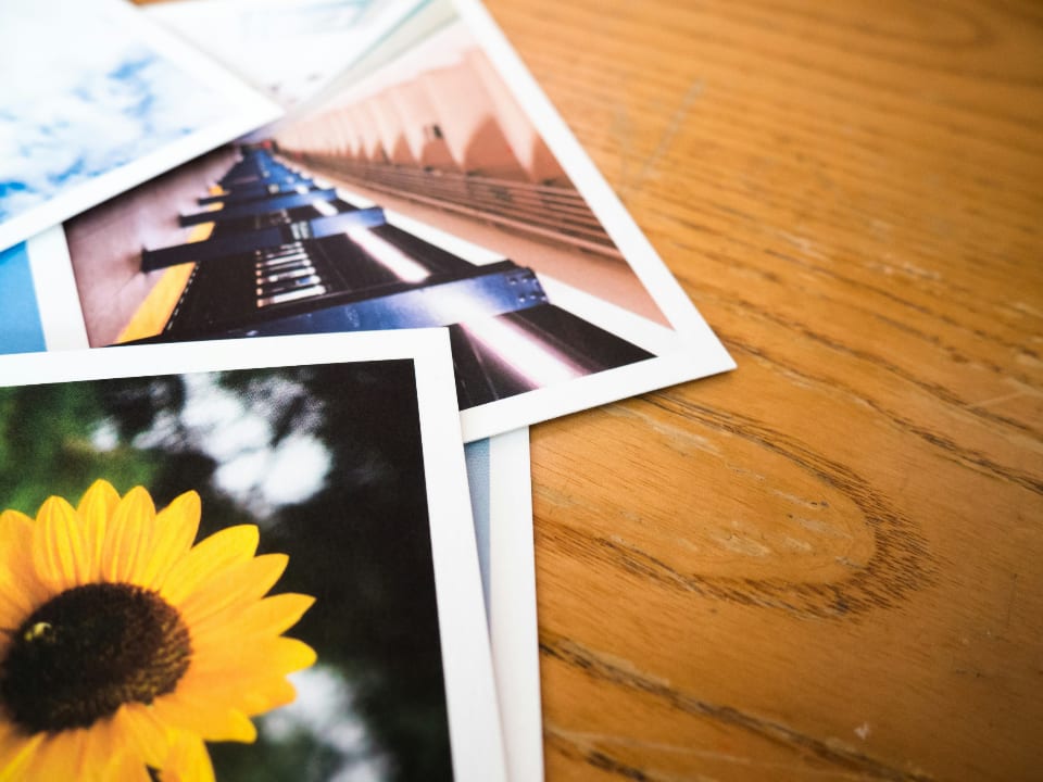 Zwei Papierabzüge liegen auf einer Holzfläche, oben eine Treppe, darunter eine Sonnenblume