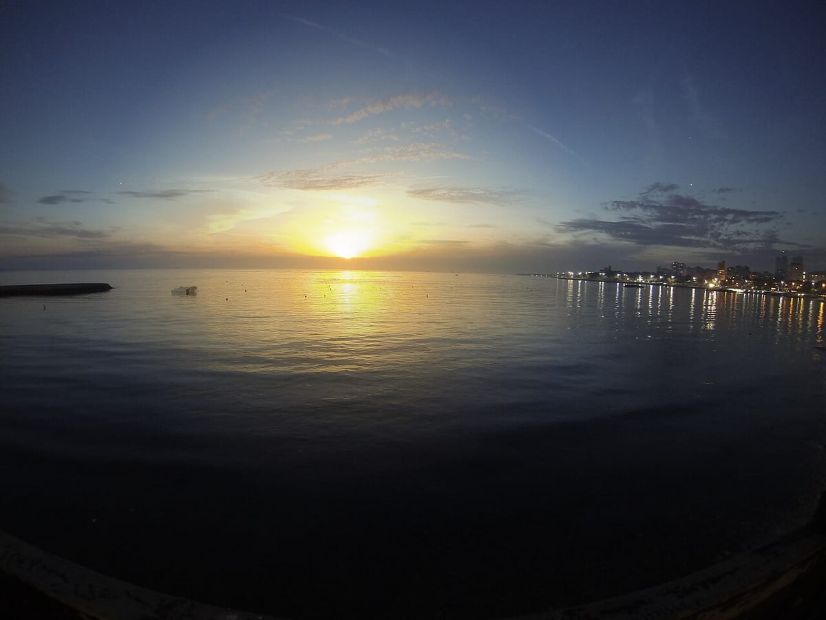 Eine Doppelbelichtung: Sonnenuntergang über Wasser, das Motiv liegt gespiegelt über sich selbst